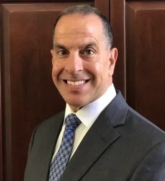 A man in suit and tie smiling for the camera.